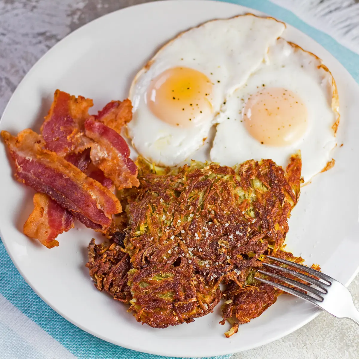 Large square angled overhead of the homemade hash browns plated in a 2 egg breakfast.
