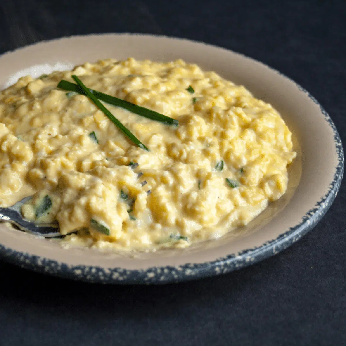 Large image of creamy Gordon Ramsay scrambled eggs with chives on top.
