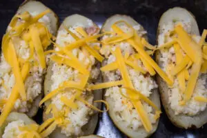 filled baked potatoes topped with cheese and ready to bake.