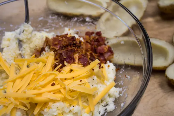 Make the twice baked potato filling combining cheese, bacon or ham, and dairy with the scooped potato.