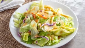 Best Benihana ginger salad dressing copycat recipe served on a white plate over salad mix.