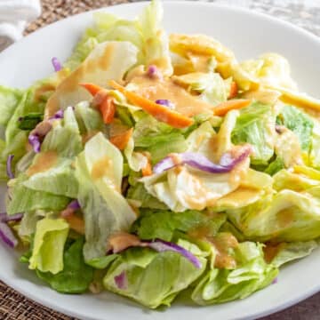 Best Benihana ginger salad dressing copycat recipe served on a white plate over salad mix.