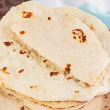 Soft homemade flour tortillas stacked in a tortilla warmer and ready to build your favorite taco night tacos.
