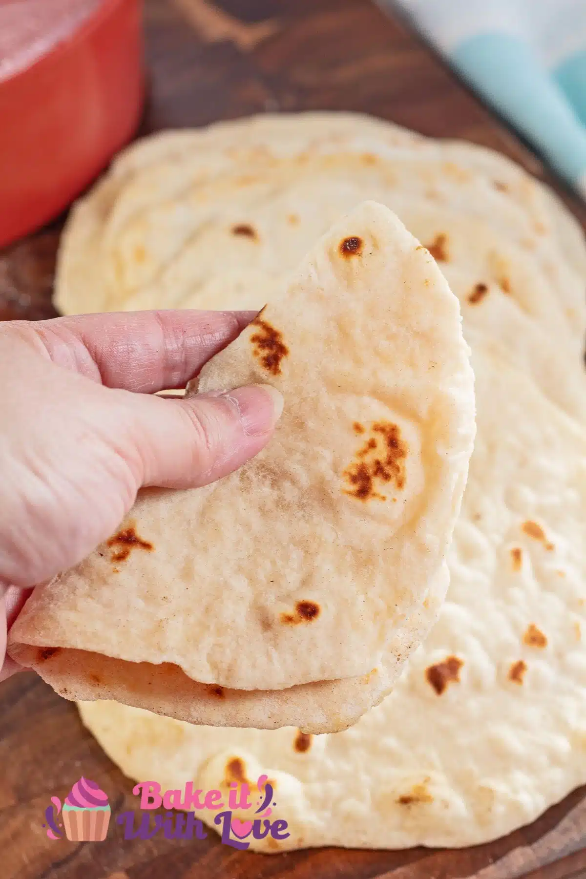 Homemade flour tortillas recipe after rolling and frying to cook with one folded in a hand.