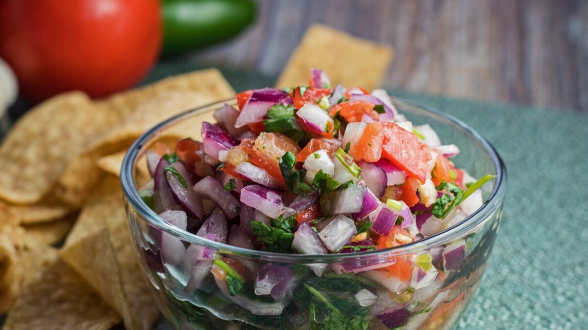wide sideview image of pico de gallo with chips and fresh vegetables.
