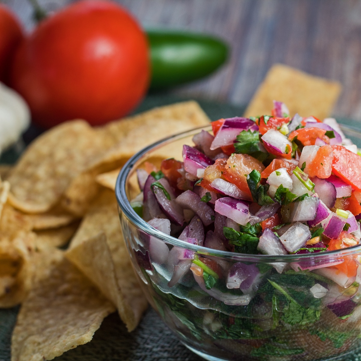 large square sideview image of pico de gallo with chips and fresh vegetables.