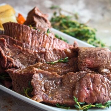 crockpot yankee pot roast served on a white plate with sliced meat at the front and the vegetables stacked behind
