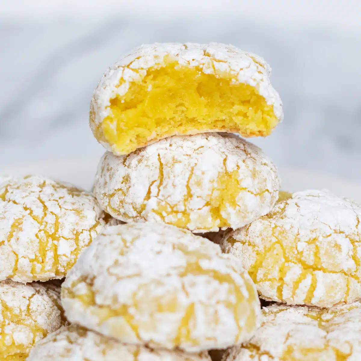 Supermjuka citrongrädde cheese crinkle cookies staplade med en tugga som visar den gula mitten av den översta kakan.