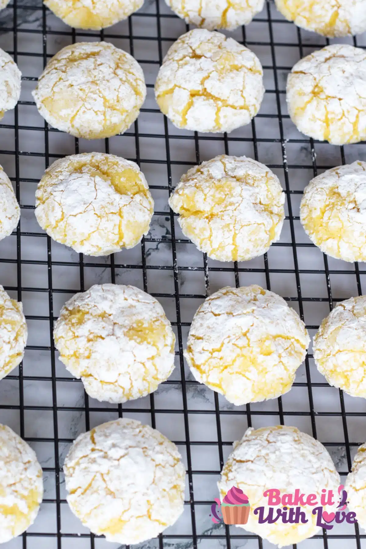 Baked lemon cream cheese crinkle cookies on wire cooling rack.
