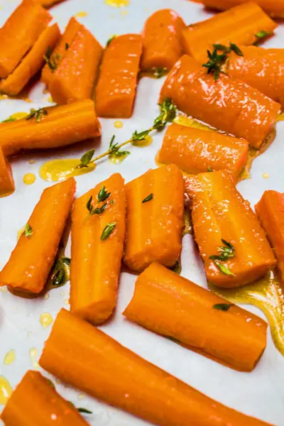 Easy Honey and Herb Oven Roasted Carrots sliced and laid out in a single layer on a rimmed baking sheet