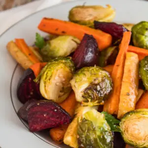 roasted vegetable medley of beets carrots parsnips and brussel sprouts served in a white plate