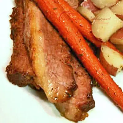 sliced oven baked brisket served with carrots and potatoes.