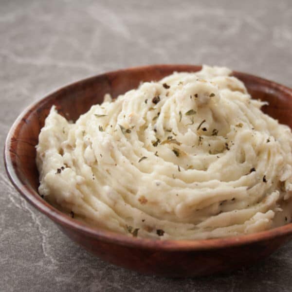 Immagine quadrata di purè di patate all'aglio arrosto in una ciotola di legno.
