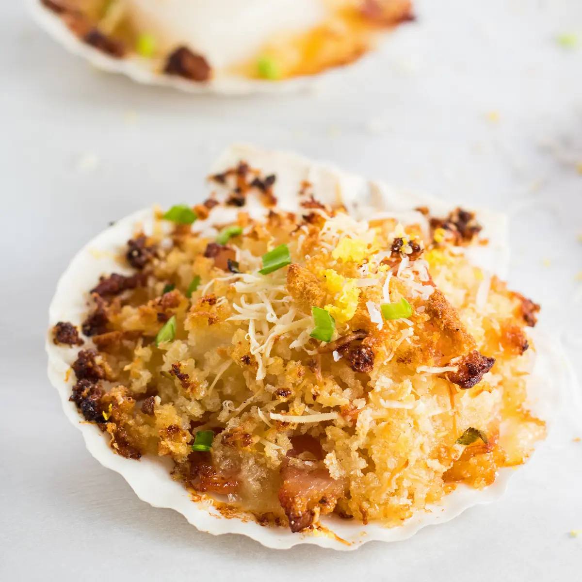 Large square image centered slightly overhead on breaded stuffed scallop served in clam shell