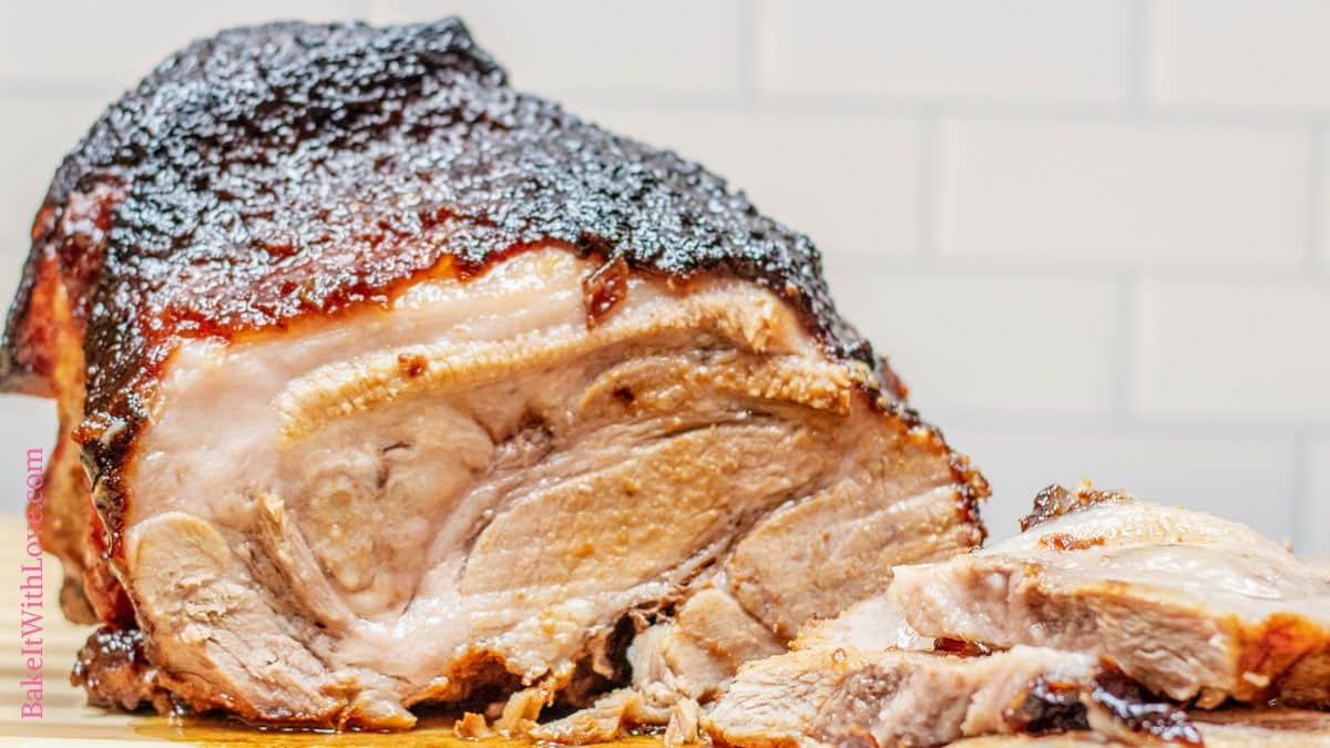 A wide image of a caramelized brown sugar and Dijon-crusted pork roast with a caramelized top and sliced pieces revealing tender meat.