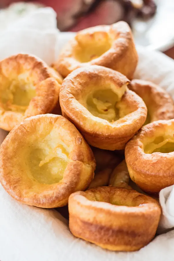 Tall closeup image of traditional yorkshore puddings served in towel lined bowl.