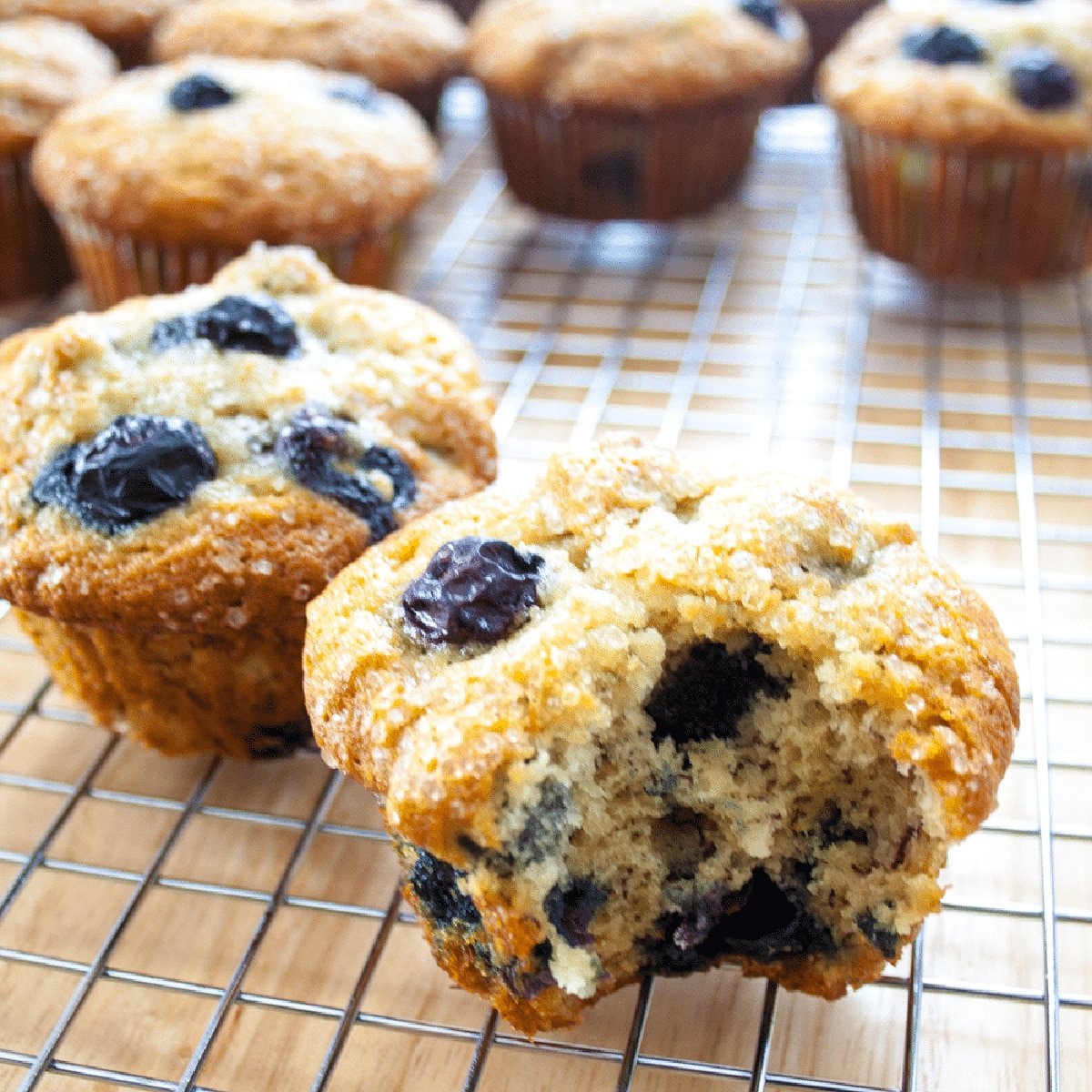 Muffin blueberry pisang terbaik didinginkan di rak kawat dengan muffin depan robek terbuka.