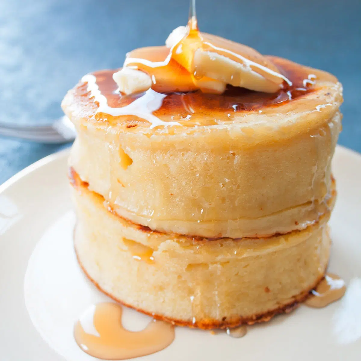 Stacked Japanese fluffy pancakes with butter and syrup.