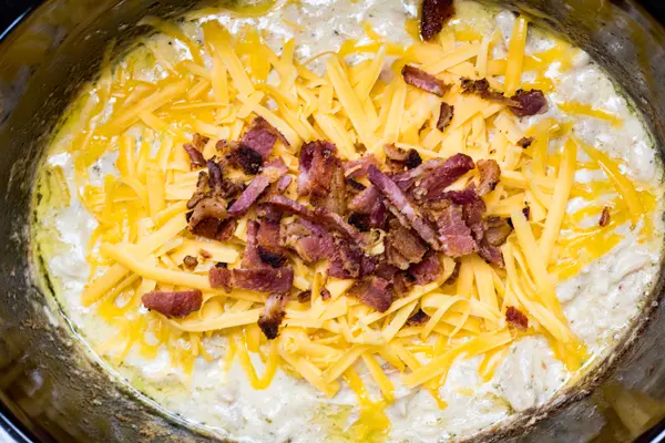 slow cooker crack chicken after cooking and shredding with cheese and bacon added.