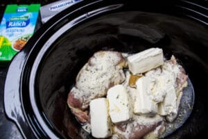 Ingredientes iniciales de pollo crack en olla de cocción lenta agregados a la olla de cocción lenta y listos para calentar.