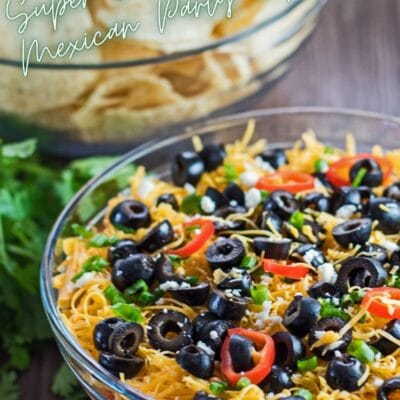 pin with 7 layer dip in clear bowl with chips in background.