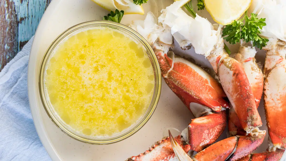 Drawn butter served in clear bowl with crab legs.