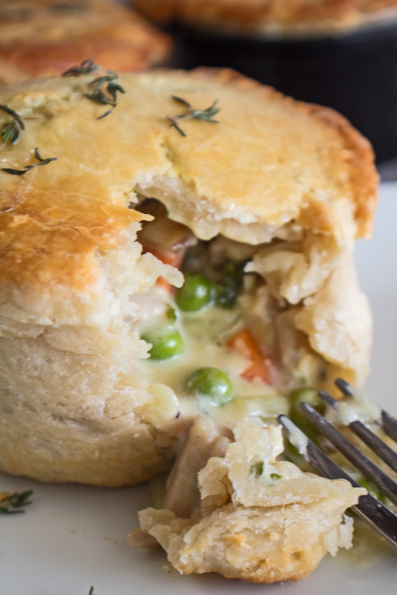 Individual pot pie opened with a fork showing the dlieciously creamy pot pie filling.