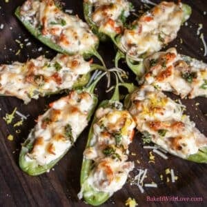 Delicious lobster jalapeno poppers on a wooden serving tray with garnish of Parmesan and lemon zest sprinkled over them.