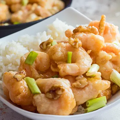 small square image of the panda express honey walnut shrimp served in a white bowl with green onions as garnish