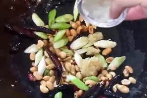 adding cut green onion roasted peanuts minced garlic ginger crushed red bell pepper flakes and sesame seed oil