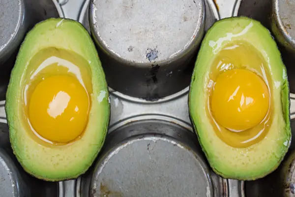 Photo showing 2 sets of avocados with eggs upside down  on a muffin tin.