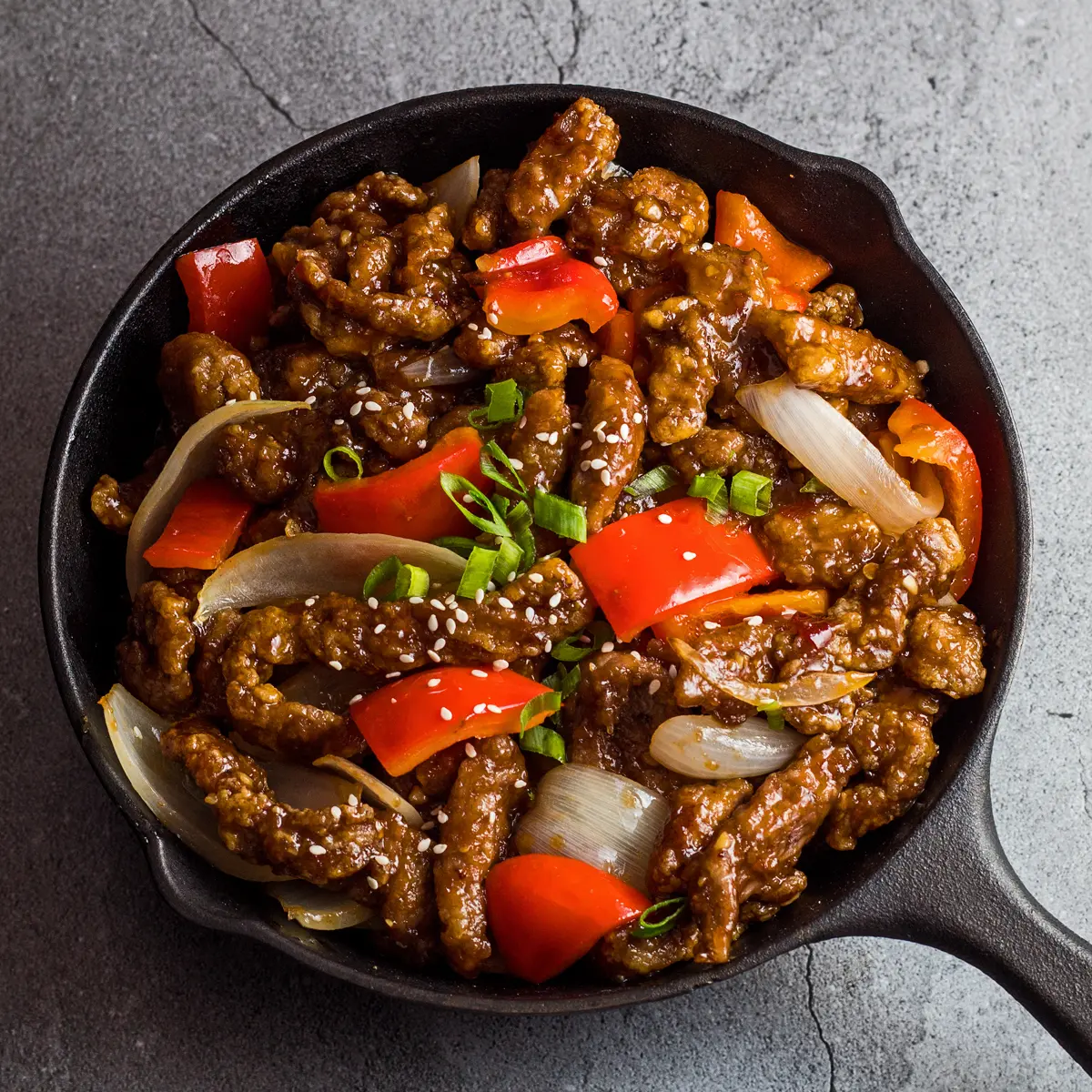 Large square overhead image of the panda express beijing beef served with wok fried crispy chunks of beef red pepper and onion in beijing sauce.