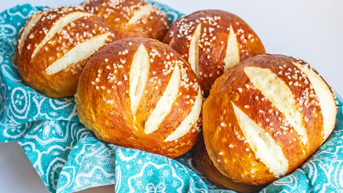 Chewy pretzel buns baked and topped with salt then served in a lined basket.