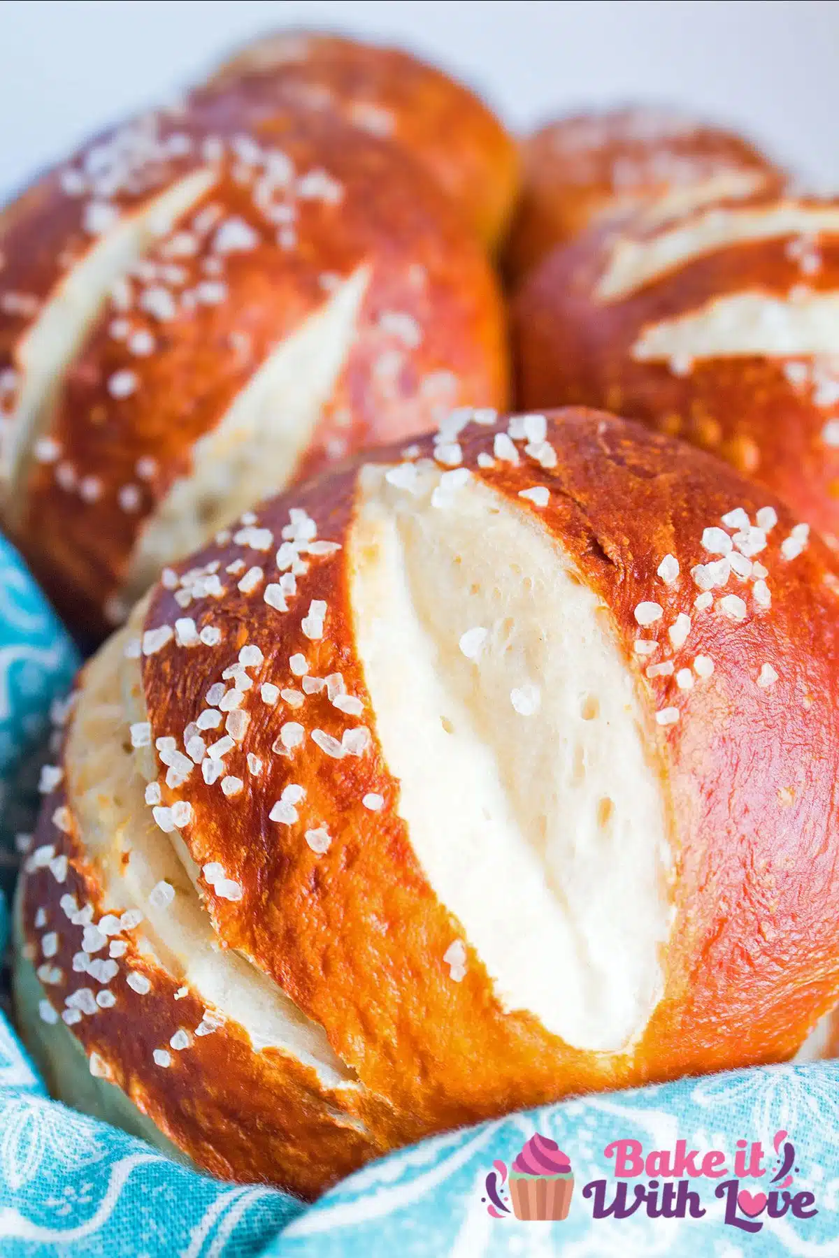 Best delicious pretzel buns or pretzel rolls recipe to make for fantastic burgers & sandwiches, shown served in a bandana-lined basket.