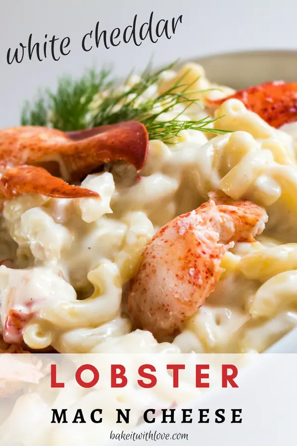 Lobster mac and cheese in a white bowl with chunks of lobster and fresh dill on top.