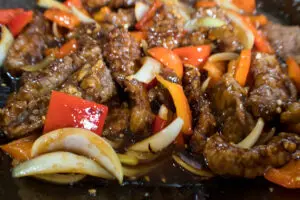 beef peppers and onion being wok stir fried with beijing sauce