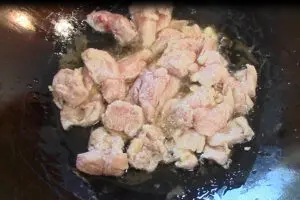 corn starch coated chicken breast pieces being wok fried in oil before the vegetables are stir fried