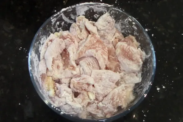 cut chicken breast coated in corn starch and ready to be wok fried