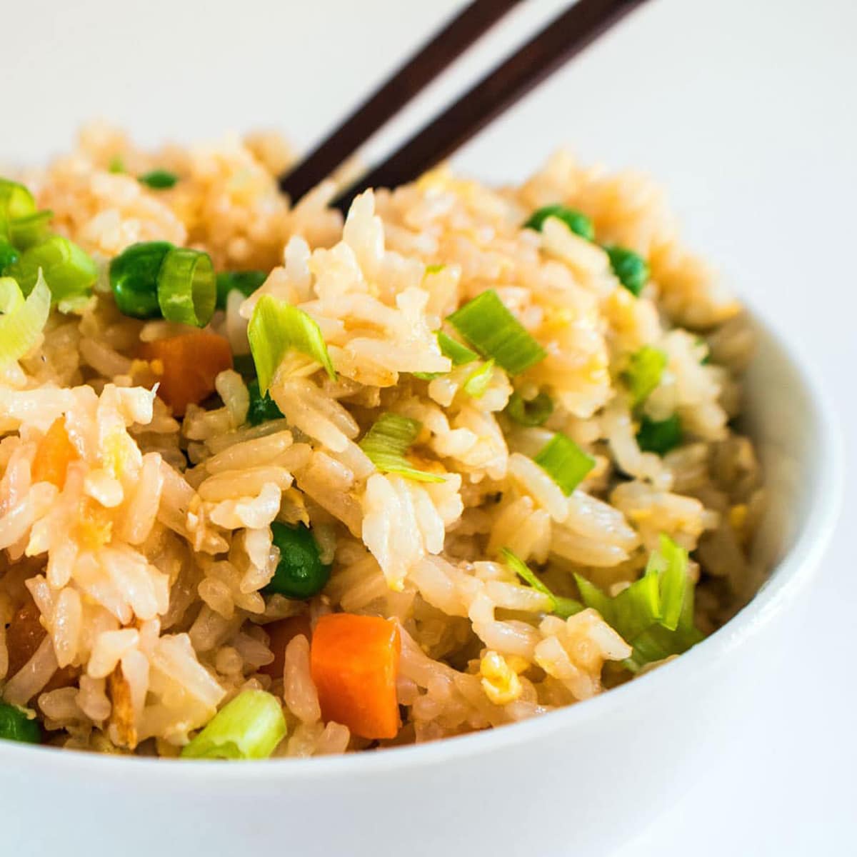 Fyrkantig närbild bild av en vit skål fylld med stekt ris.