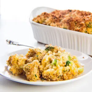 Square image of a tasty cheesy chicken broccoli rice casserole served on white plate.