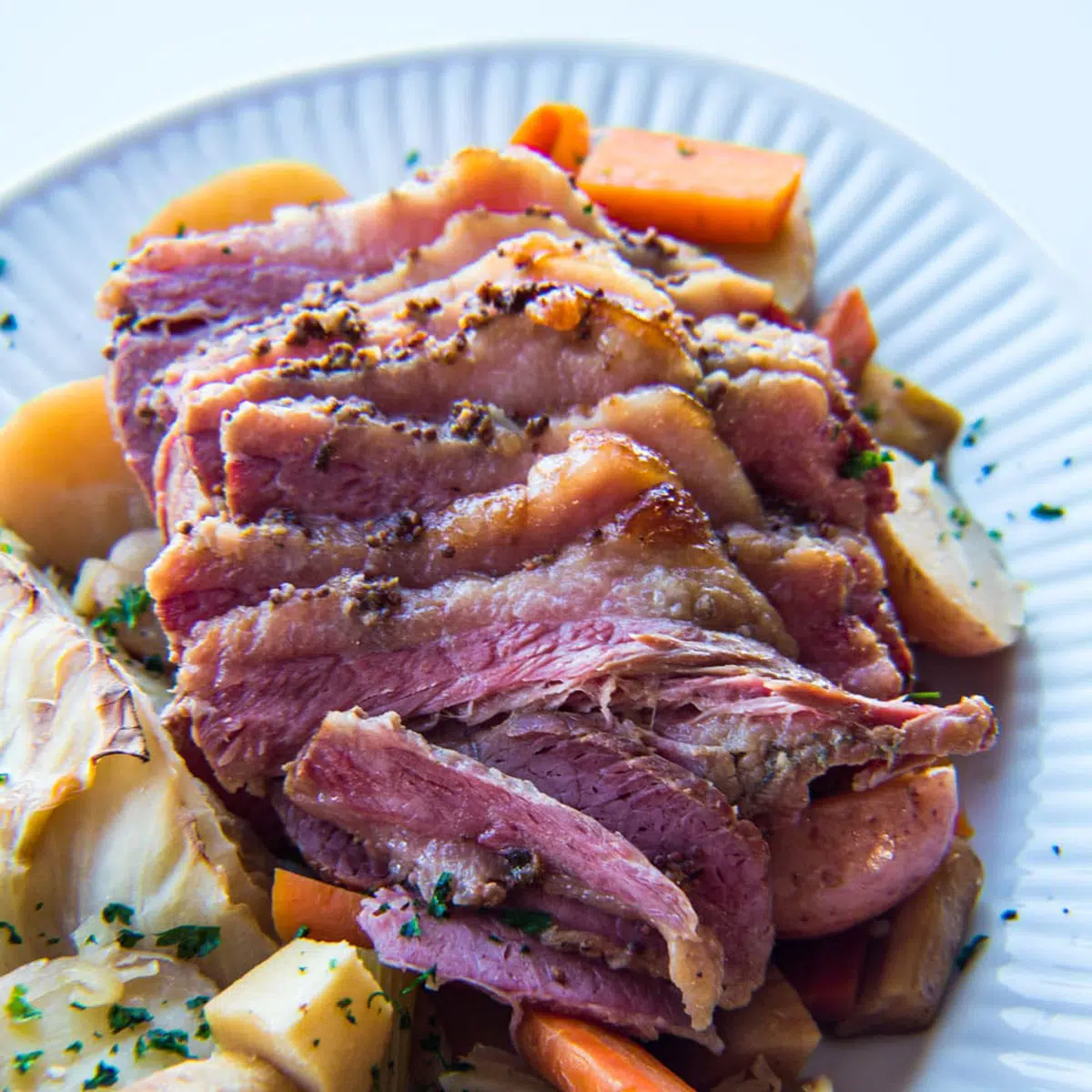 Carne en conserva y repollo en un plato blanco con zanahorias.