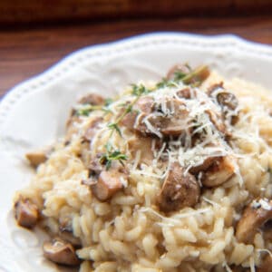Square image of mushroom risotto on a white plate.