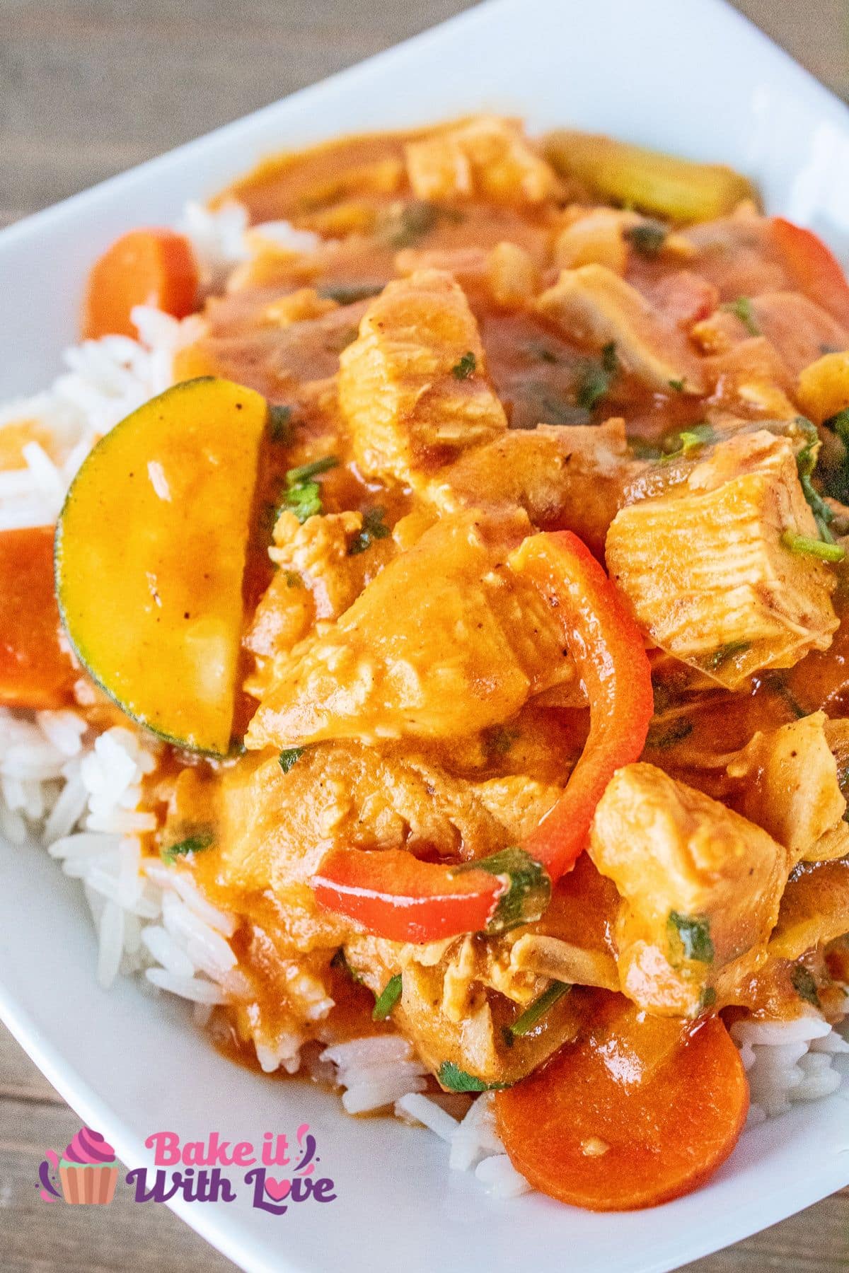 Tall image of leftover turkey curry over white rice, on a white plate.