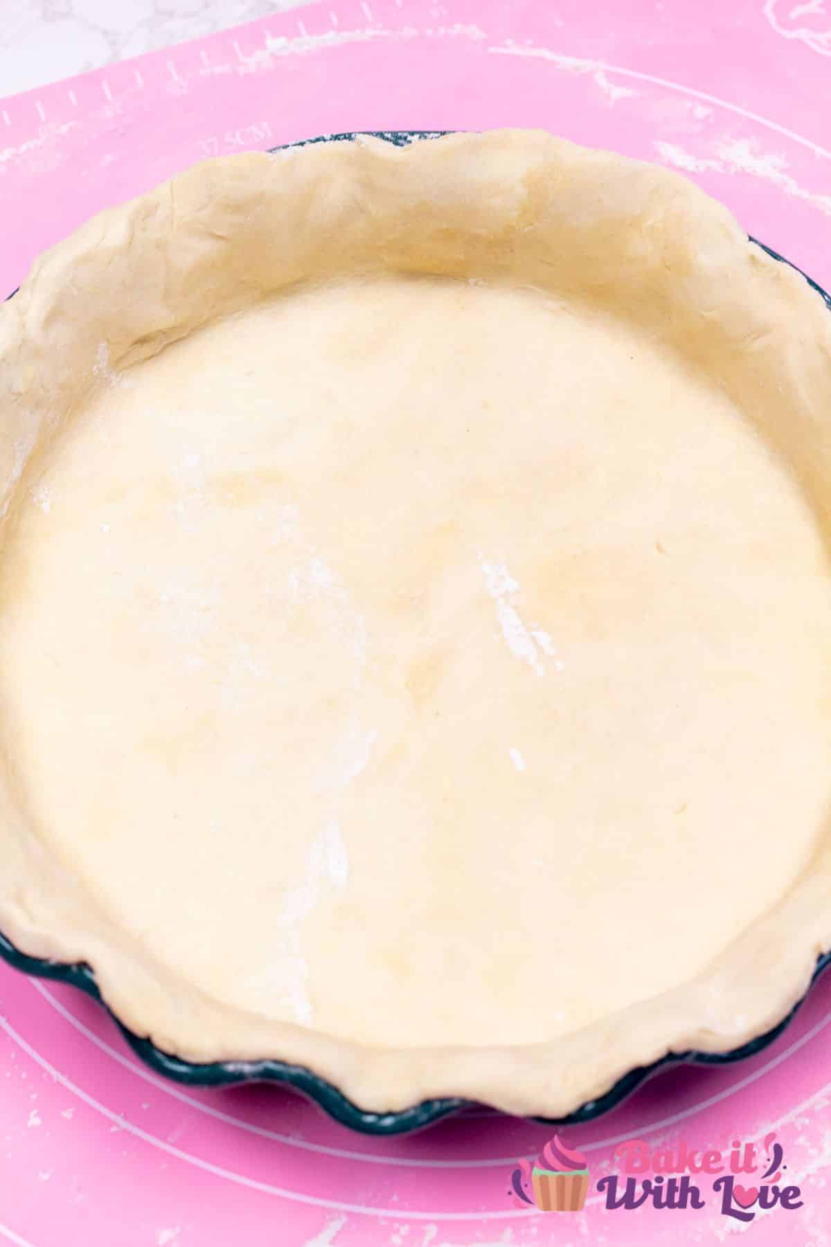 A tall image showing homemade all-butter pie crust dough that had been rolled out and pressed into a pie dish.