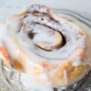 Square image of cinnamon roll with icing.