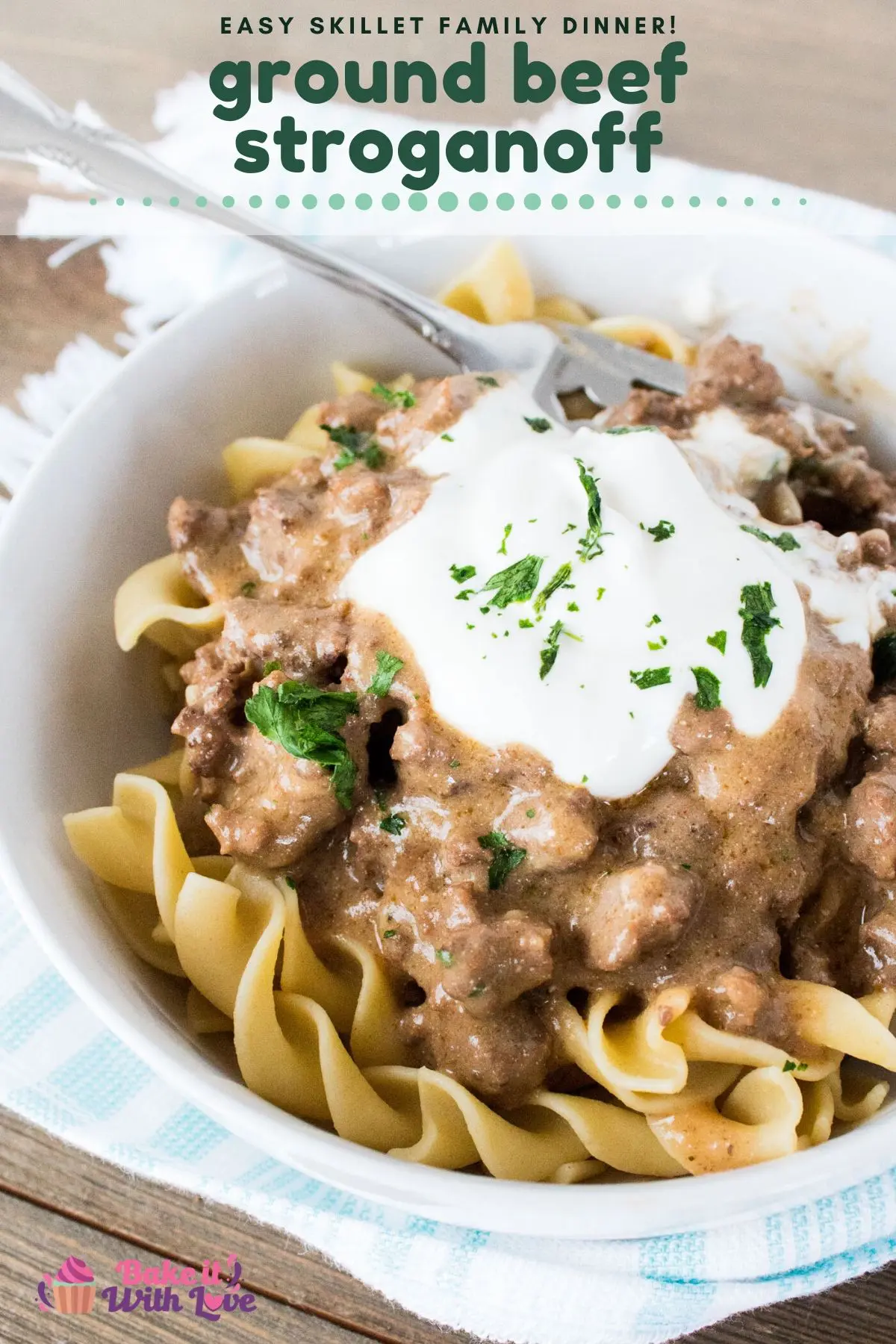 Hearty ground beef stroganoff served in white dish with sour cream dollop and parsley garnish on top.