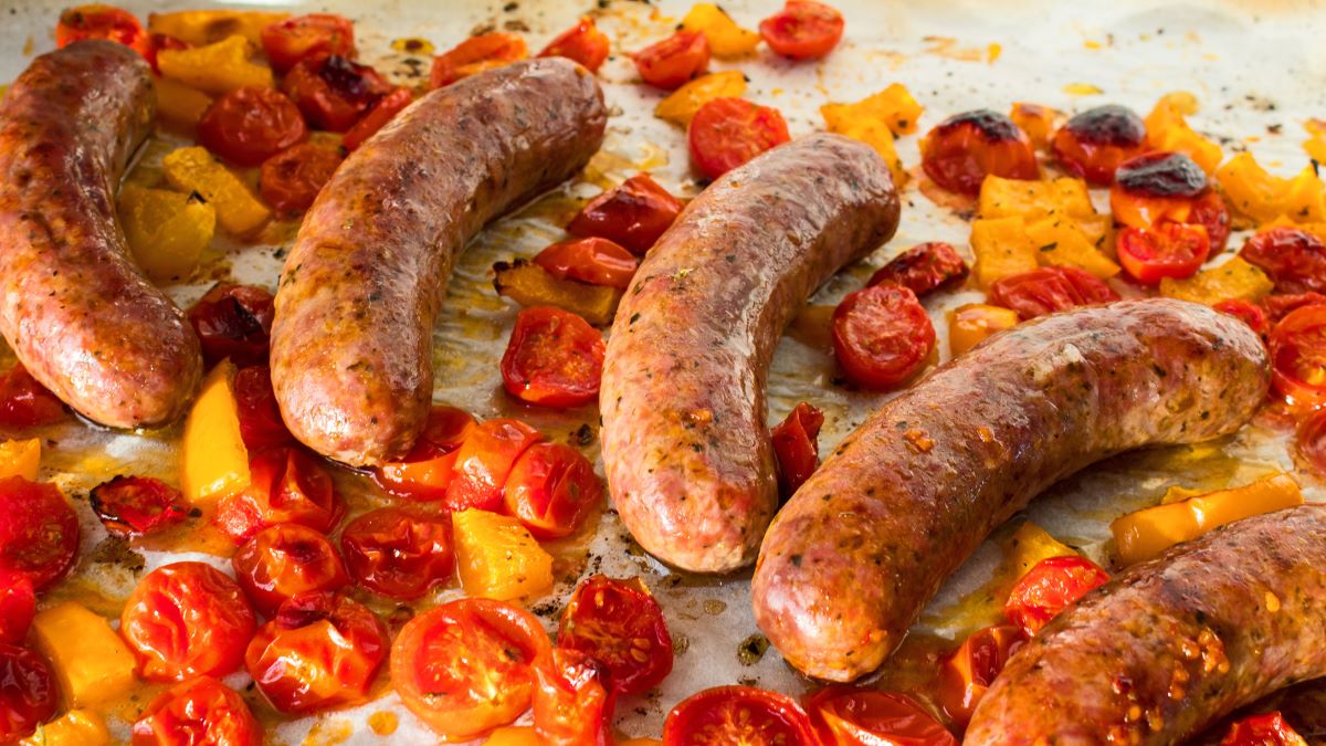 Savory baked italian sausages right out of the oven with cherry tomatoes and peppers.