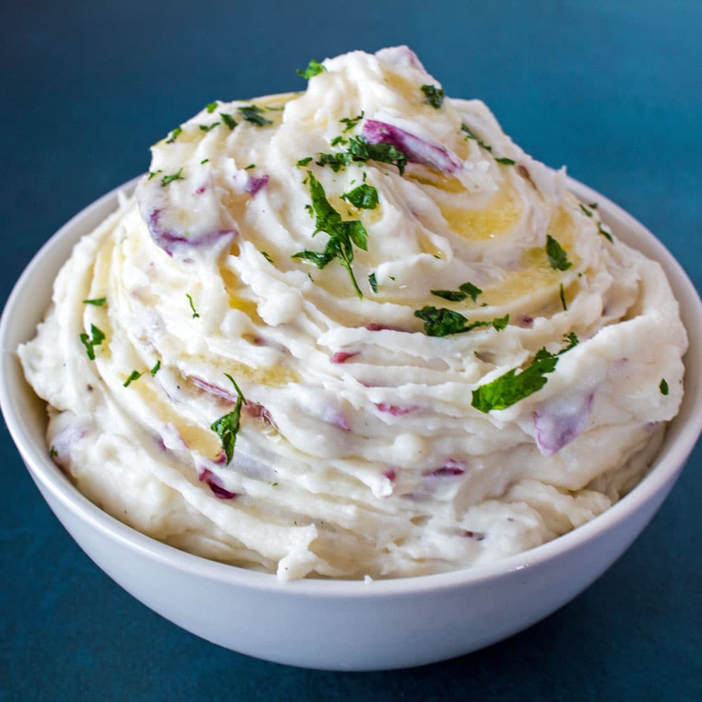 These delightfully creamy Garlic Red Skin Mashed Potatoes are loaded with roasted garlic and cream cheese for the ultimate silky texture with just enough lumps to let the red skin potato flavor shine!