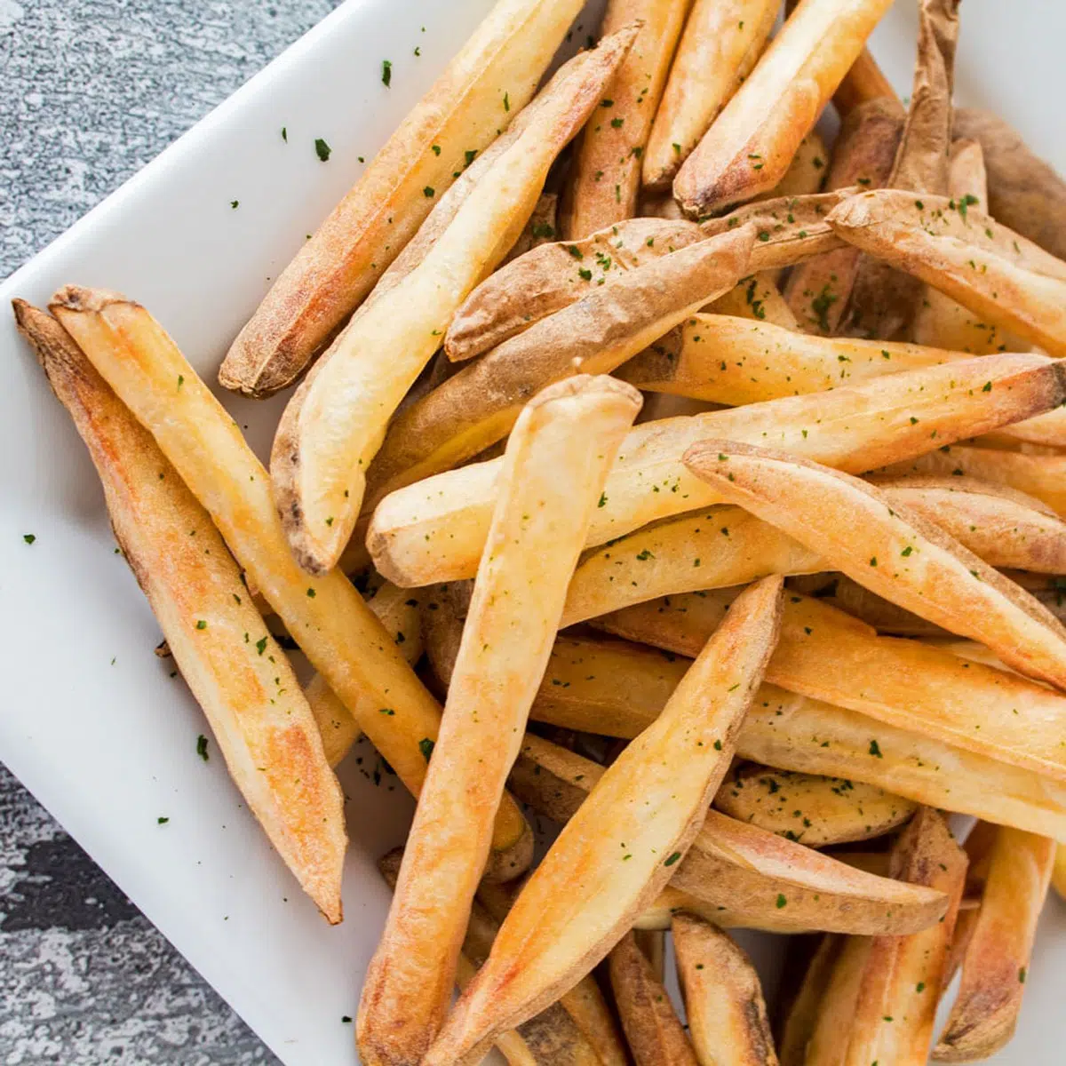 Air fried french fries on a white plate.
