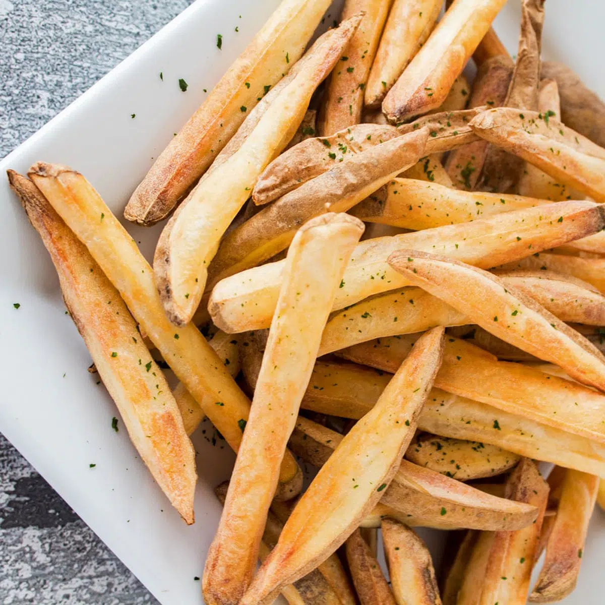 Luftstekta pommes frites på en vit tallrik.